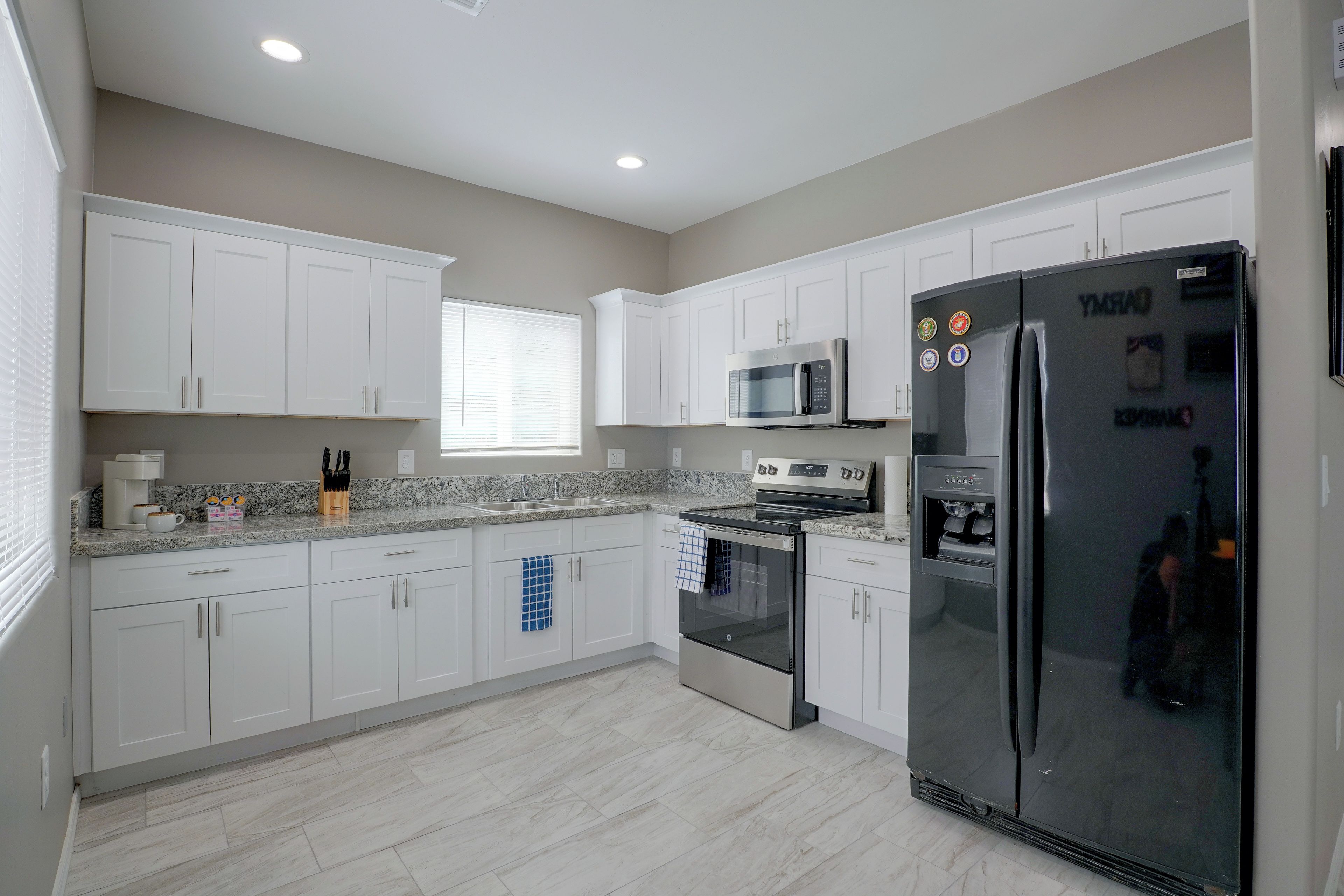 A modern kitchen with white cabinets, a black refrigerator, a microwave, and a built-in oven.