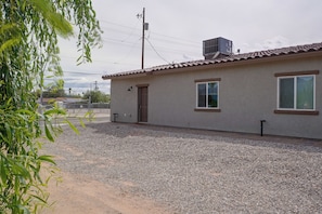 A single-story building with a gravel driveway, a door, and a window with a shutter. - Townhome 1 Mi to Midtown & Botanical Gardens! (Tucson)