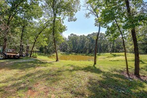 A natural landscape with a pond, trees, and a trailer.