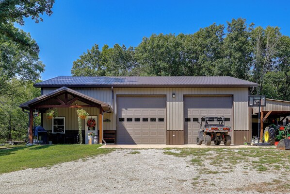 A two-story building with a garage, a covered porch, and a basketball hoop.