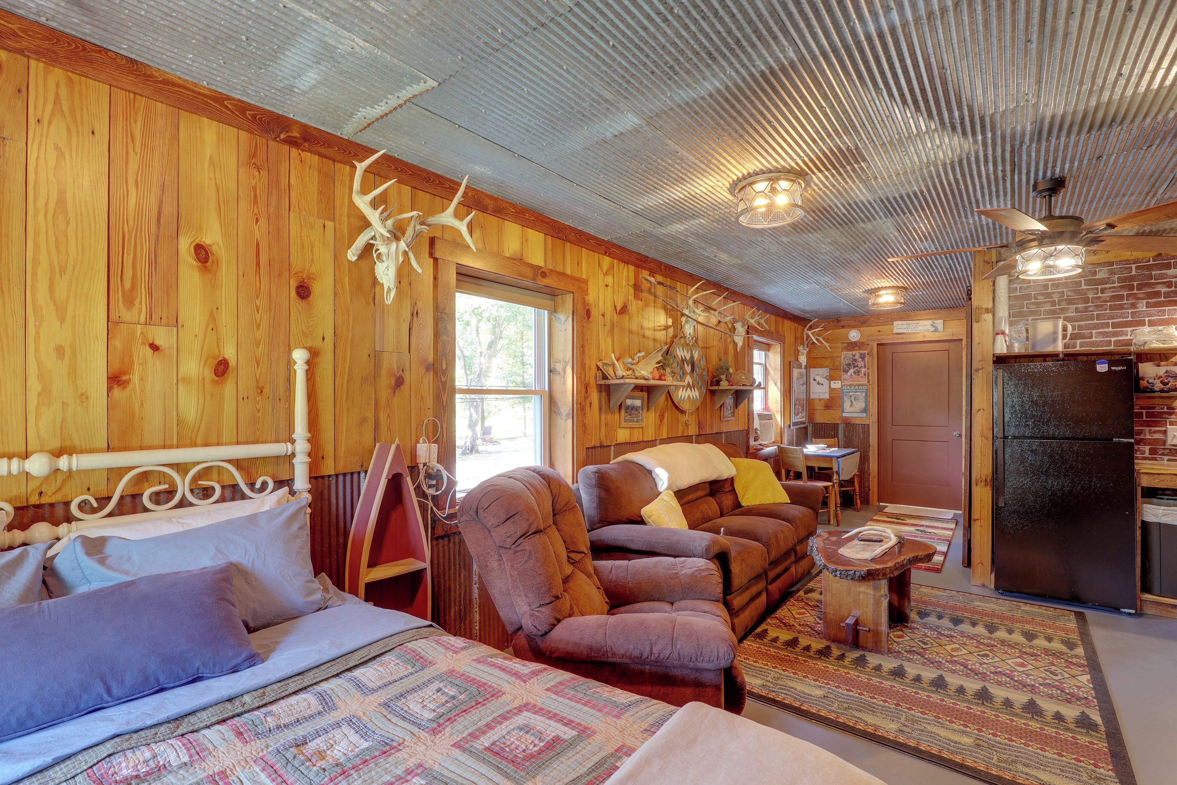 Un intérieur de chalet chaleureux comprenant un lit, deux canapés, un coin repas et un réfrigérateur.
