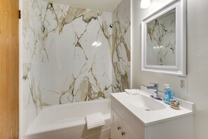 Un bagno con una parete in marmo, un lavandino, uno specchio e un asciugamano.