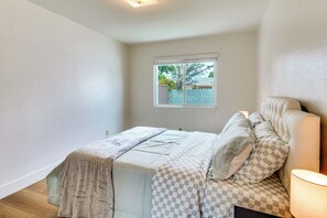 A bedroom with a bed, a window, and a nightstand with a lamp. - Fullerton Suite w/ Private Yard, Extended Stays (Fullerton)