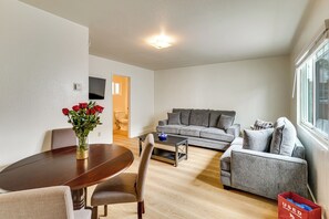 A modern living room with a dining table, grey sofa, and a vase of red roses. - Fullerton Suite w/ Private Yard, Extended Stays (Fullerton)