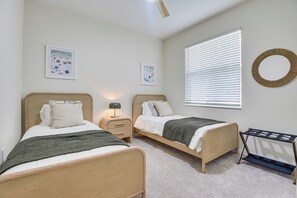 A bedroom with two single beds, a bedside table with a lamp, a wall-mounted circular mirror, and two framed pictures. - Private Community w/ Pool, Near Gulf Beaches (Palmetto)
