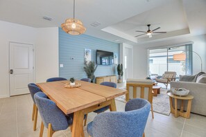 A modern living room with a wooden dining table, blue chairs, a sofa, and a ceiling fan. - Private Community w/ Pool, Near Gulf Beaches (Palmetto)