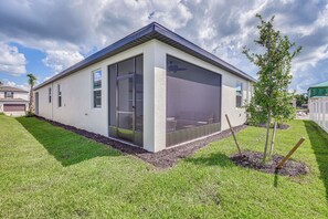 A modern single-story house with a large sliding glass door, a small patio area, and a well-maintained lawn. - Private Community w/ Pool, Near Gulf Beaches (Palmetto)