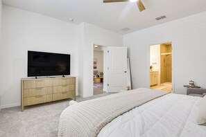A bedroom with a bed, a television on a wooden dresser, and a bathroom with a shower. - Private Community w/ Pool, Near Gulf Beaches (Palmetto)
