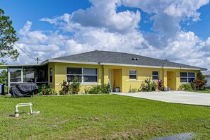 A yellow single-story house with a covered porch, a lawn, and a clear sky.