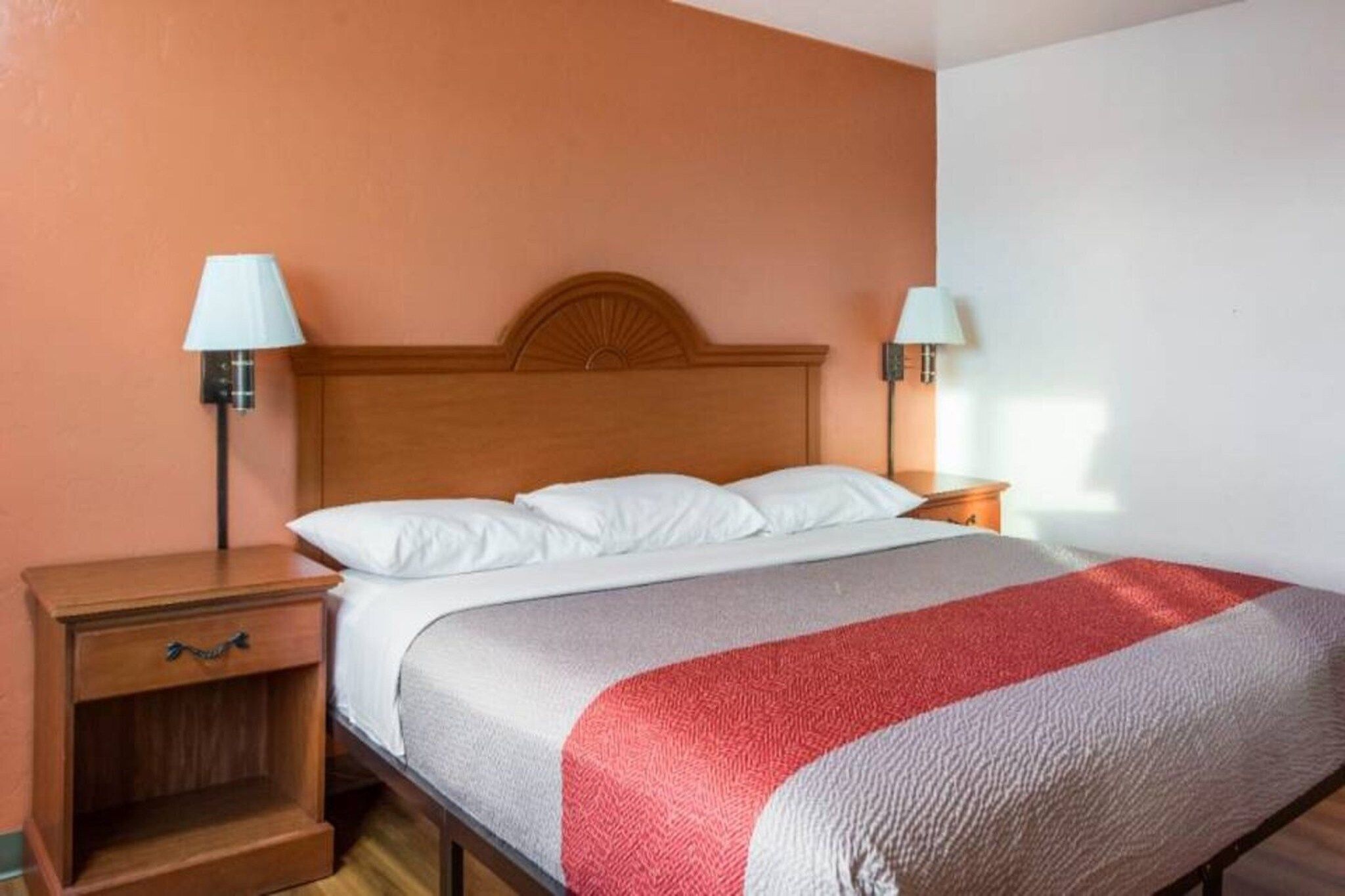 A hotel room with a bed, two bedside tables, and lamps.