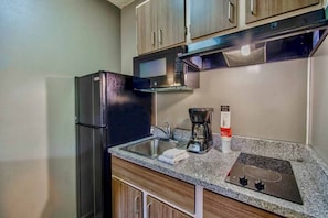 A compact kitchen with a refrigerator, stove, sink, and coffee maker. - 1 Queen Bed | ADA/Tub (PHOENIX)