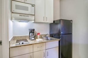 Una cocina con microondas, cafetera y refrigerador.