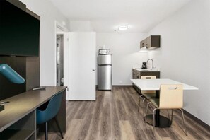 Eine kleine Küche mit Kühlschrank, Spüle und einem Essbereich mit Stühlen.
