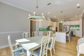 A dining area with a white table and chairs, a chandelier, and a kitchen with teal cabinets and stainless steel appliances. - Pool & Hot Tub at Gated Waverly Home (Waverly)