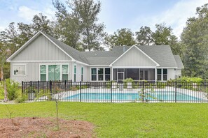 A two-story house with a swimming pool, surrounded by a black metal fence and a grassy lawn. - Pool & Hot Tub at Gated Waverly Home (Waverly)