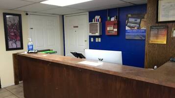A reception desk with a computer, a water bottle, and a framed picture on the wall.
