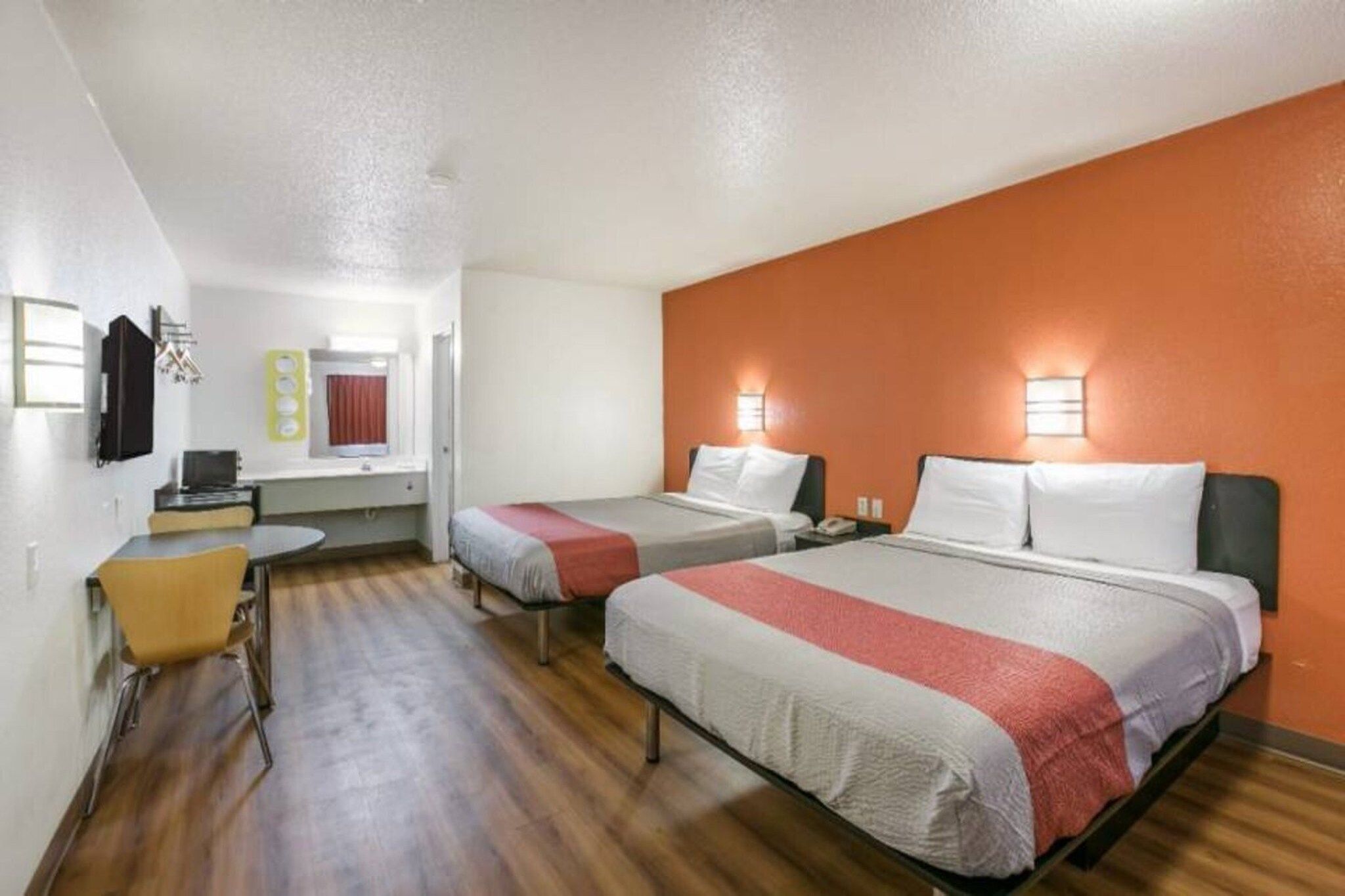 Une chambre d’hôtel avec deux lits, un bureau, une chaise et un téléviseur.
