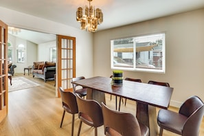 A dining area with a wooden table and leather chairs, a chandelier, and a window with blinds. - 4BR Fullerton Home, 9 Mi to Cal State (Fullerton)