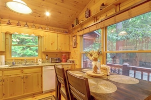 L'intérieur d'un chalet en bois comprend une cuisine, un coin repas et de grandes fenêtres.