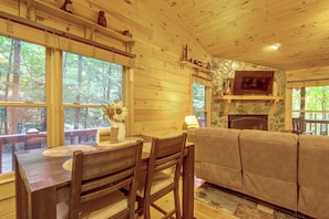 A wooden interior with a dining table, chairs, a sofa, and a fireplace. - Pet-Friendly Cozy Cabin Retreat  Hot Tub & Trails (Cherry Log)