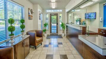 A reception area with a counter, seating, potted plants, and a television.