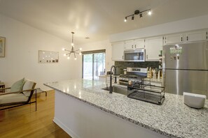 A modern kitchen with granite countertops, stainless steel appliances, and a dining area with a chair and table. - 10 Mi to Dtwn Little Rock! Patio & Fire Pit (Mabelvale)