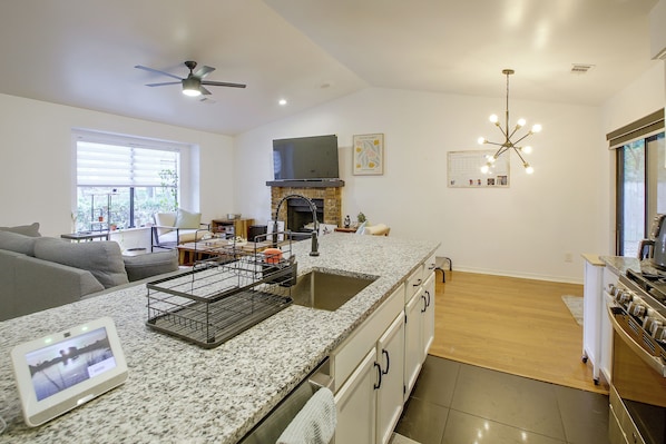 A modern kitchen with granite countertops, a built-in oven, and a dining area with a sofa.