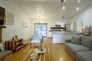 Una cocina moderna con electrodomésticos de acero inoxidable, un comedor con mesa y sillas de madera, y una sala de estar con un sofá gris.