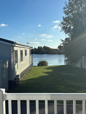 A lakeside view with a white building, a grassy area, and a clear sky. - Charming Tattershall Mobile Home 3 Bedrooms, Private Entrance, Shared Pool (Tattershall)