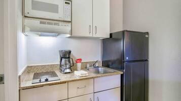 Una cocina con microondas, cafetera y refrigerador.