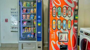 Una máquina expendedora con varios snacks y una máquina expendedora de helados cerca.