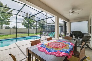 Ein Poolbereich mit Tisch, Stühlen und Deckenventilator.