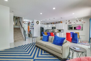 A modern living room with a sofa, a coffee table, and a striped rug. - 8 Mi to Disney! Whimsical Home w/ Pool & Game Room (Kissimmee)