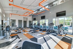A gym with various exercise equipment, large windows, and a checkered floor pattern. - 8 Mi to Disney! Whimsical Home w/ Pool & Game Room (Kissimmee)