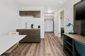 A compact kitchen with a dining area, a TV, and a walk-in closet. - 1 King Bed | Non-Smoking, Kitchen (Tempe)