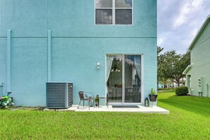 A building with a blue exterior, a sliding glass door entrance, a small patio with a table and chairs, and a large air conditioning unit. - Pool Access! Steps from Upper Tampa Bay Trail (Tampa)