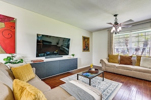 A living room with a flat-screen TV, sofa, coffee table, and a ceiling fan. - Pool Access! Steps from Upper Tampa Bay Trail (Tampa)