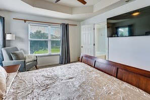 A bedroom with a bed, a chair, a window with blinds, a door, and a television. - Pool Access! Steps from Upper Tampa Bay Trail (Tampa)