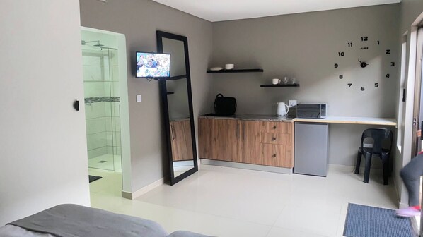Um espaço de estar compacto com cozinha compacta, televisão na parede e porta para área de banho.