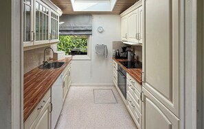A narrow kitchen with wooden countertops, white cabinets, and a window with a view of greenery. - 4 bedroom awesome home in Stege (Stege)