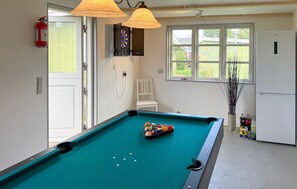 A pool table with balls, a dartboard, a chair, a window with a view, and a refrigerator. - 4 bedroom awesome home in Stege (Stege)