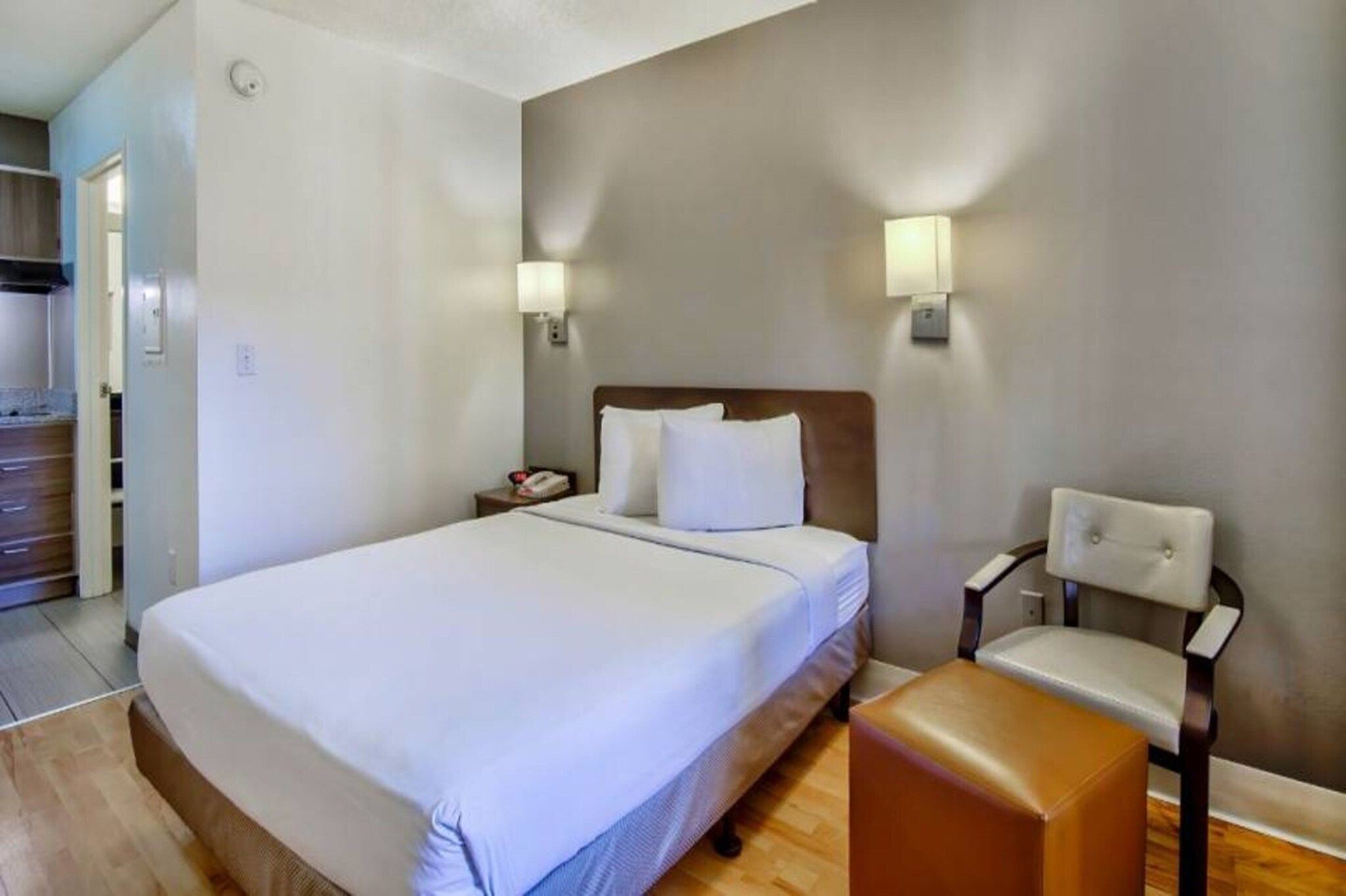 A hotel room with a large bed, bedside lamps, a chair, and a small table.