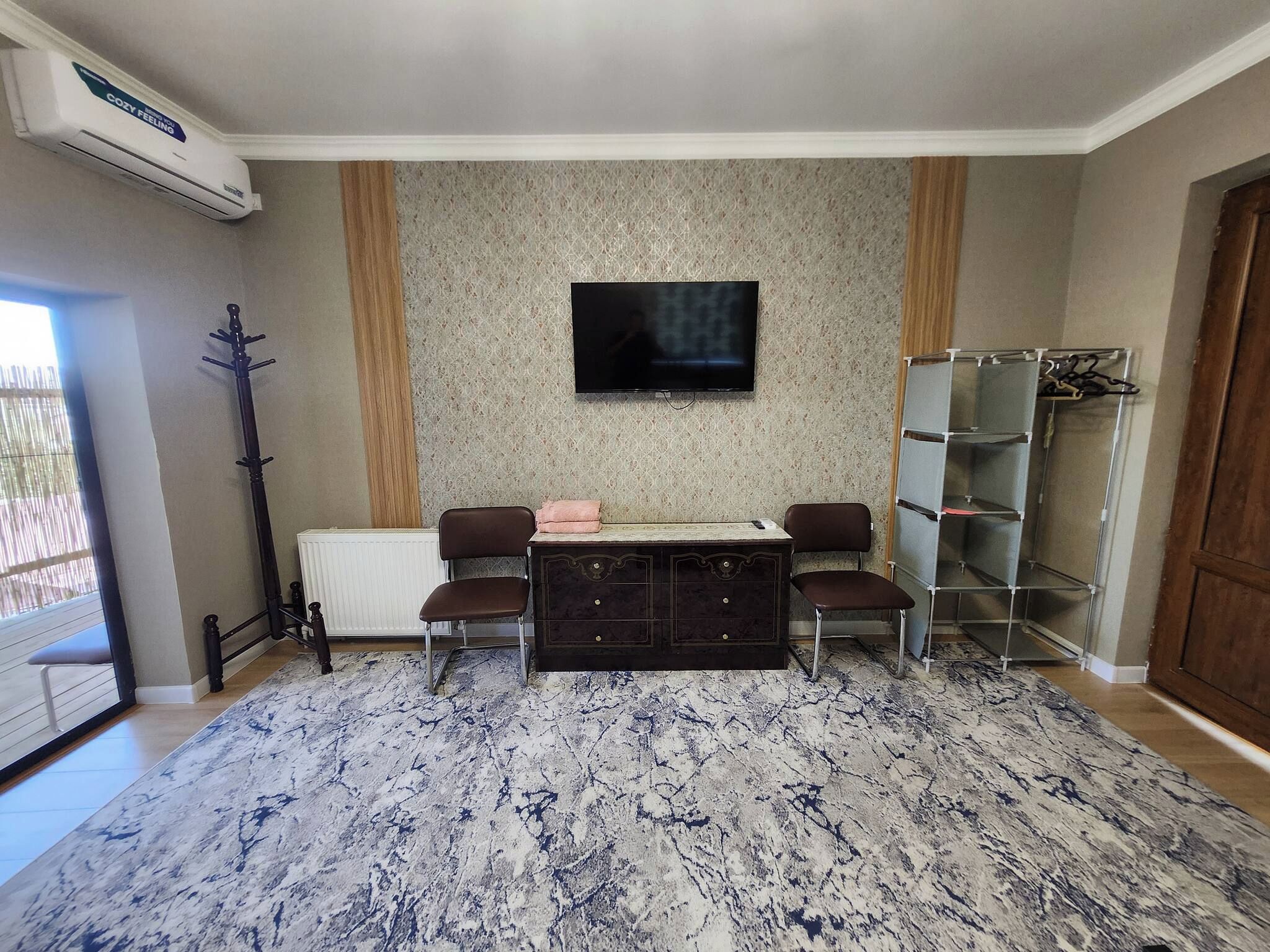 A living room with a sofa set, a flat-screen TV, a radiator, and a patterned rug.