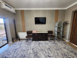 A living room with a sofa set, a flat-screen TV, a radiator, and a patterned rug.