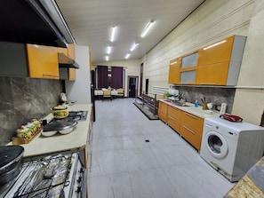 Cuina amb rentadora, zona de menjador amb taula i cadires, i vista a una altra estança.