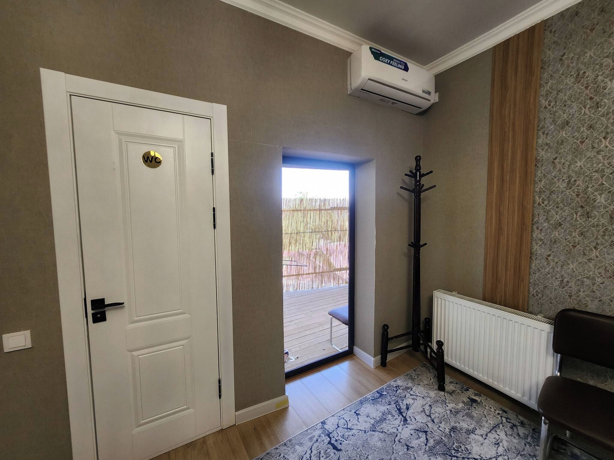 A room with a white door, a radiator, a black coat stand, and a patterned rug.