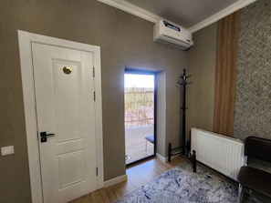 A room with a white door, a radiator, a black coat stand, and a patterned rug.