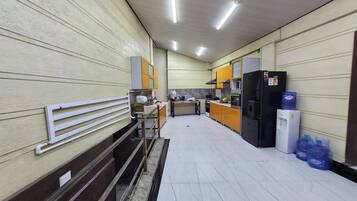 Uma cozinha limpa e bem iluminada, com eletrodomésticos modernos, um banco e um bebedouro.