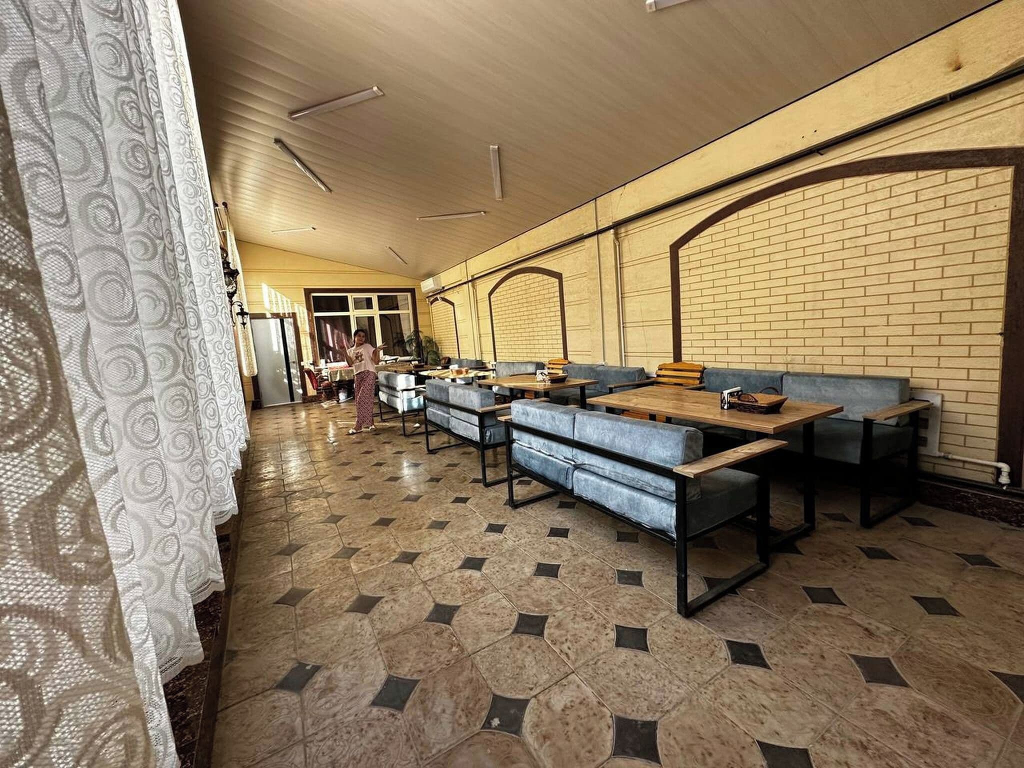 A spacious room with multiple seating areas, including sofas and tables, arranged in a linear fashion.