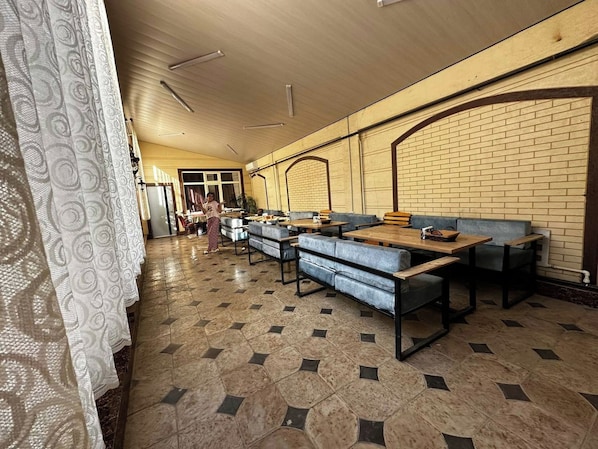 A spacious room with multiple seating areas, including sofas and tables, arranged in a linear fashion.